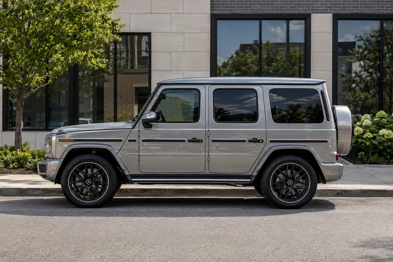 A silver Mercedes G-Class with tinted windows parked on a city street