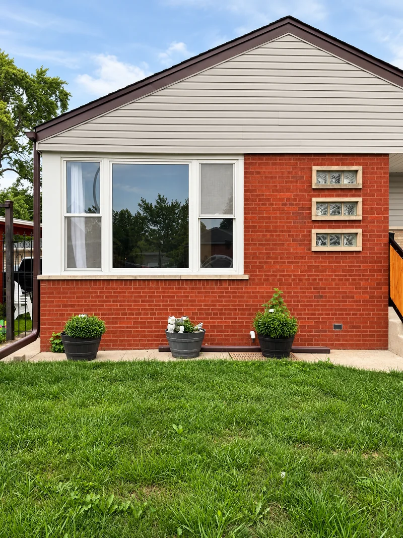 A brick bungalow whose front window Beast Auto Tints tinted