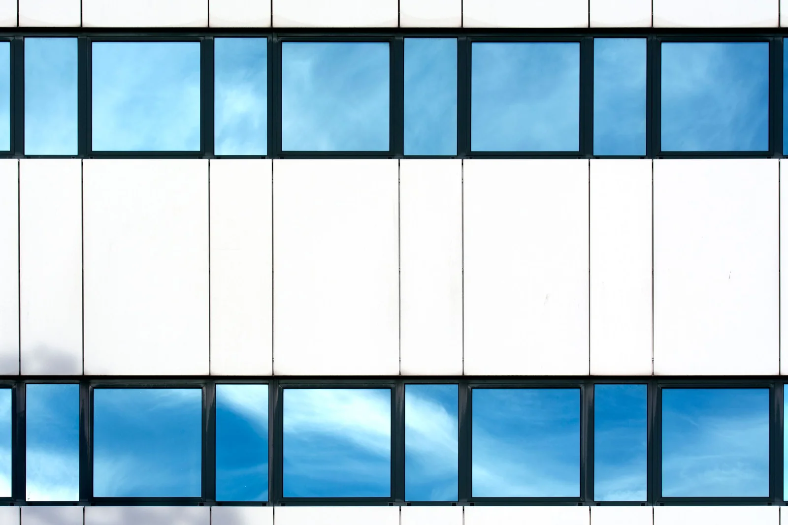 Office building windows reflecting a blue sky